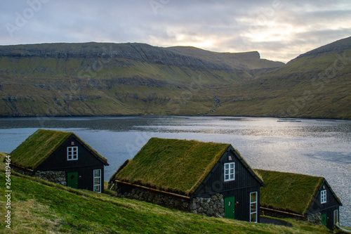 Traditional nordic Scandinavian village houses with green grass roof. Iconic scenic view of Faroe Island, Denmark, Europe. Beautiful tourist spot located at Vágar Island. Moody weather scene. 