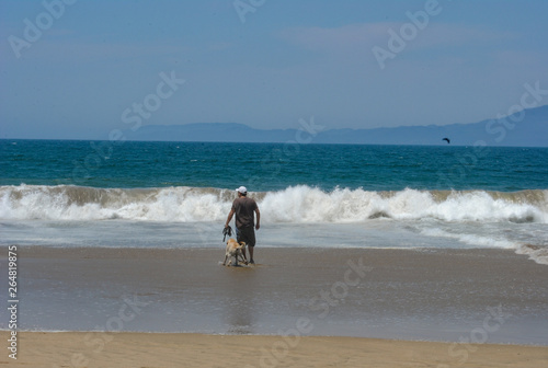 Man and dog walking in the beach in Barra de Navidad Mexico