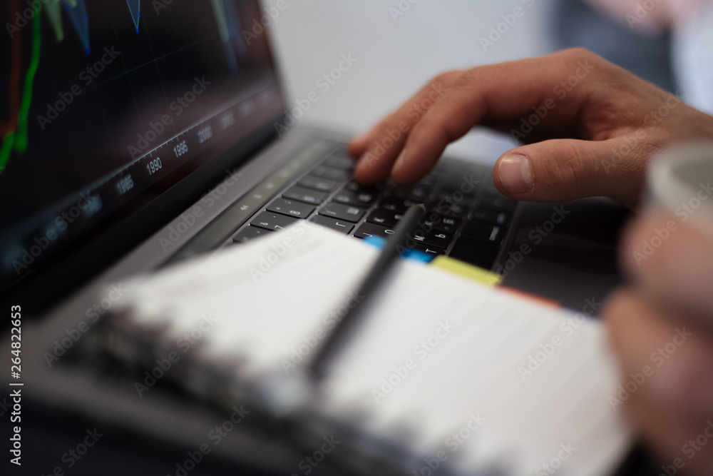 Close-up of man hands, typing on keyboard of laptop and holding mug of coffee, near notebook with black pencil. Close-up of man hands, typing on keyboard of laptop and holding mug of coffee, near notebook with black pencil.