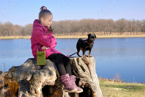 Girl sitting on a stump near the lake with a black dog PTI brabanson photo