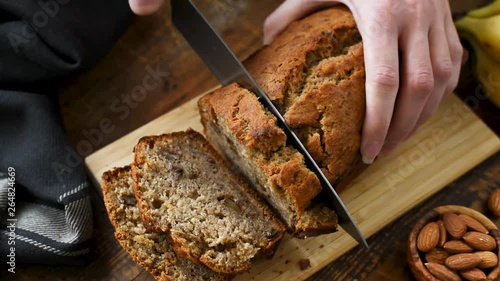 Slicing banana bread. Hands slicing homemade banana bread with nuts on a cutting board
