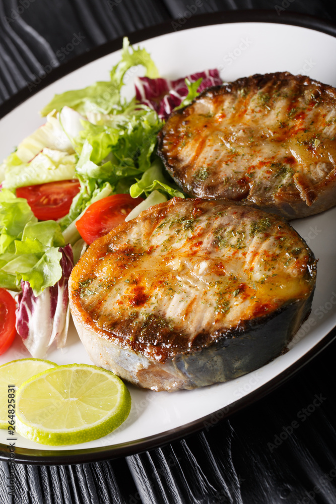 grilled sturgeon steaks with vegetable salad closeup on a plate. vertical grilled sturgeon steaks with vegetable salad closeup on a plate. vertical