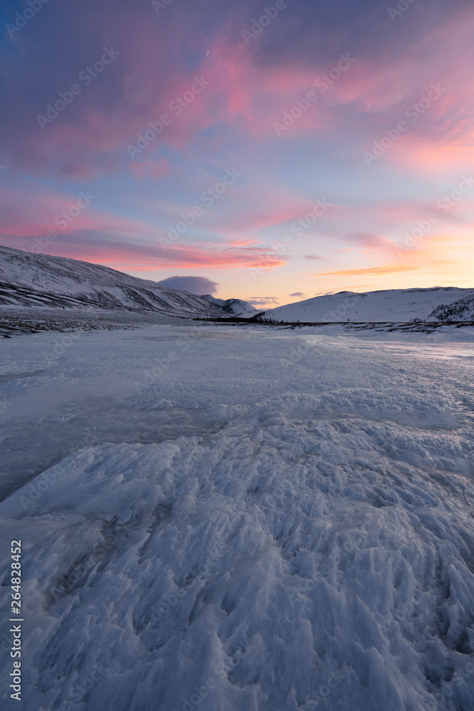 Dramatic sunset over the icy lake in the Arctic tundra. Yamal peninsula.