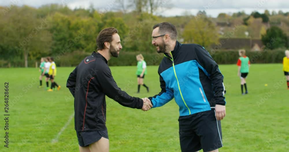 4K Team coaches shake hands & chat at beginning of youth soccer match. Slow motion. 4K Team coaches shake hands & chat at beginning of youth soccer match. Slow motion.