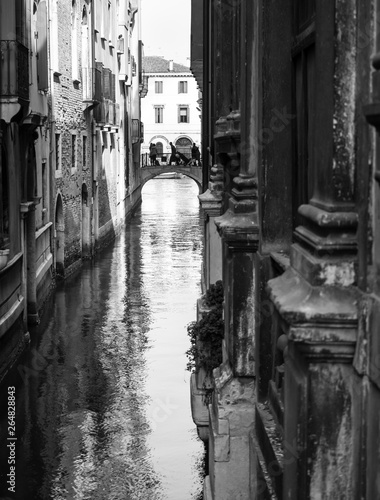 Venice, Italy: narrow canal, tourists on a small bridge in the background