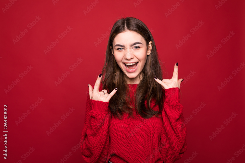 Portrait of loud sound music lover woman isolated on red background with copy space for text show her rock n roll punk sign wkn eye show tongue out Portrait of loud sound music lover woman isolated on red background with copy space for text show her rock n roll punk sign wkn eye show tongue out