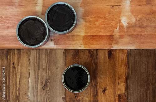 Top view on a newly opened can of wax, varnish, oil, paint on a freshly painted wooden surface. Several wood coating options, artwork, texture or background for text