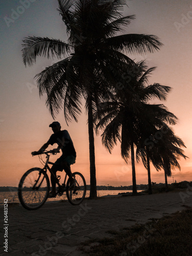 silhouette of man on bike at sunset