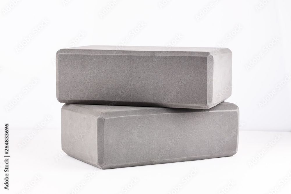 Two gray blocks for yoga on a white