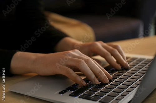 Woman using laptop at night, closeup