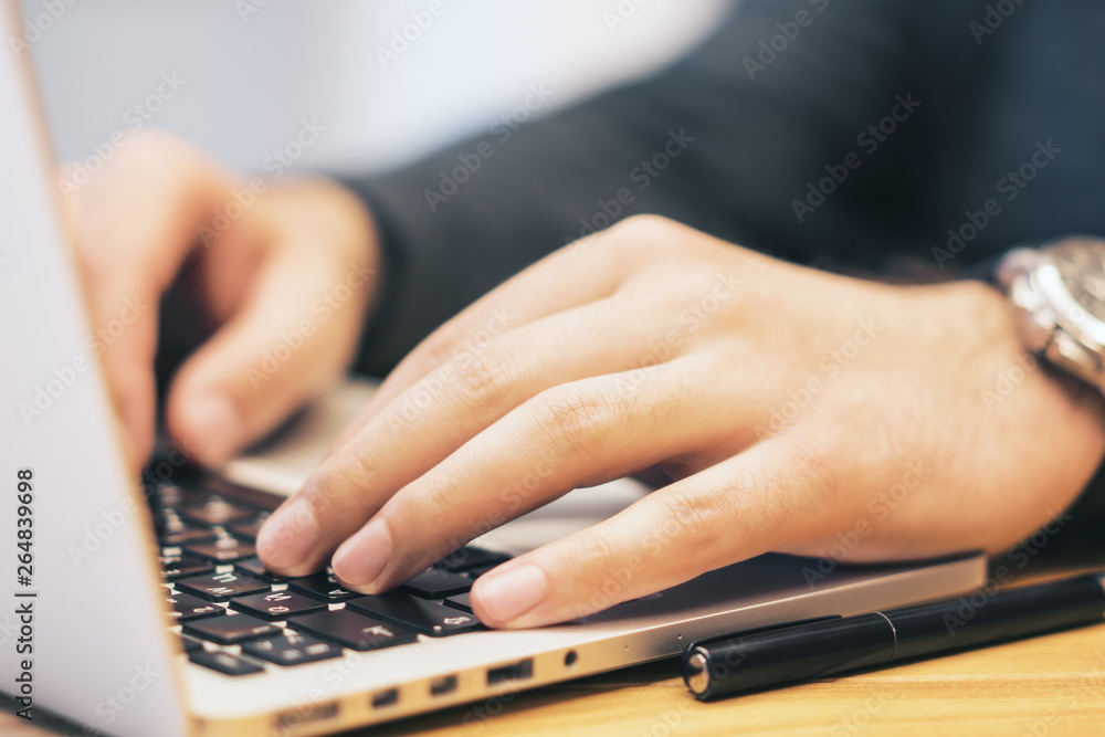 Sideview of man using laptop on desk top Sideview of man using laptop on desk top