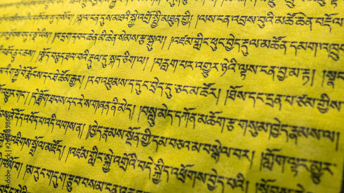 Tibetan letters on yellow textile. Religious writing. Prayer flags. Mantra. Buddhism. Calligraphy