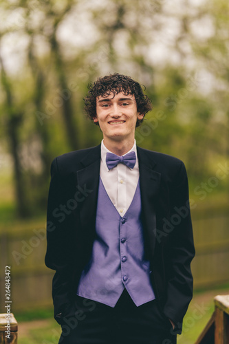 Teenage boy in tuxedo with purple bow tie and accents.