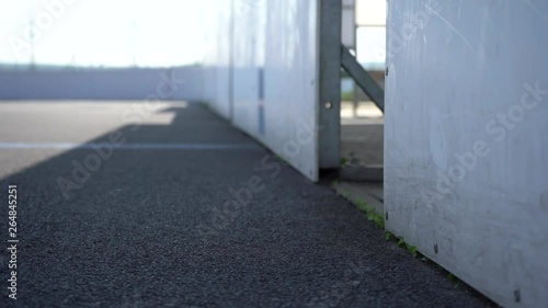  View to inline skates riding on empty playground. Outdoor inline skating on smooth concrete ground. Before the big tournament. Empty ice hockey playground - view from behind the gate. 