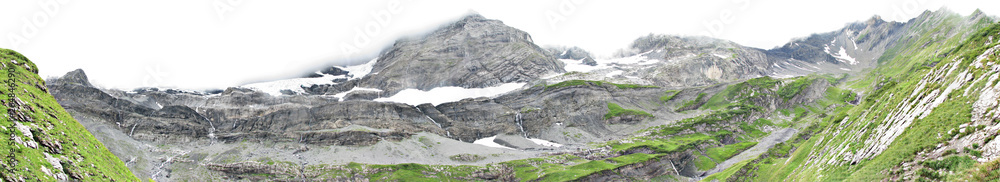 Panorama of mountain scenery with green meadows and snow-capped mountains in the Alps.