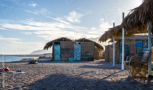 Beach huts at the blue lagoon in Dahab city in South Sinai peninsula in Egypt , those beautiful huts was built on the beach and made from bamboo and palm leaves . 