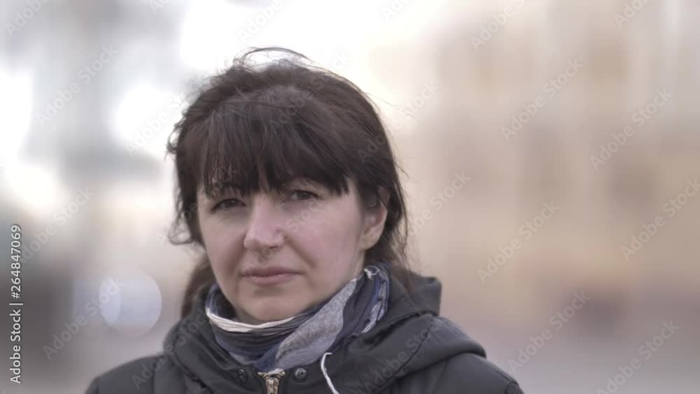 portrait of a woman turns and looking at the camera on the background of passing cars portrait of a woman turns and looking at the camera on the background of passing cars