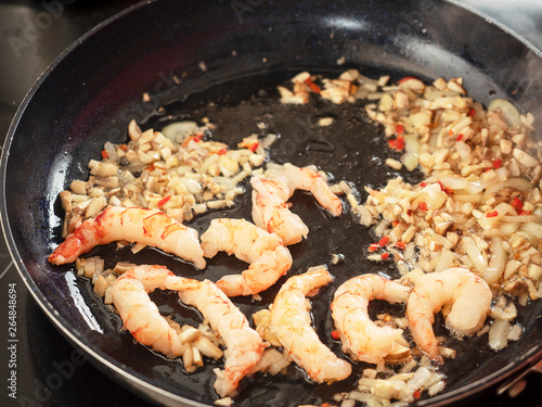 Prawns on a frying pan with chopped garlic. Close up.