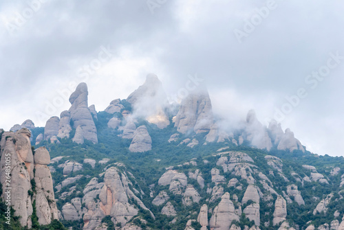 Hazy unusual mountains with green trees and cloudy sky near Montserrat Monastery Spain