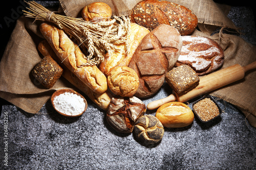 Photo Assortment of baked bread and bread rolls on rustic grey bakery table background