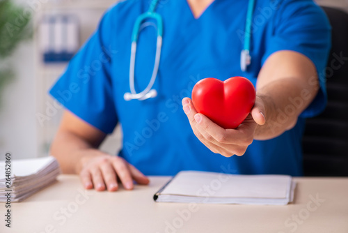 Male doctor cardiologist holding heart model 