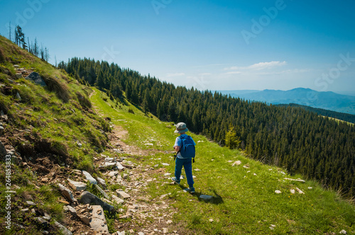 Little boy hiking alone on mountain path