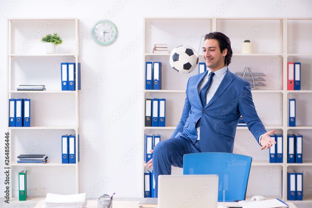 Young handsome businessman with soccer ball in the office 