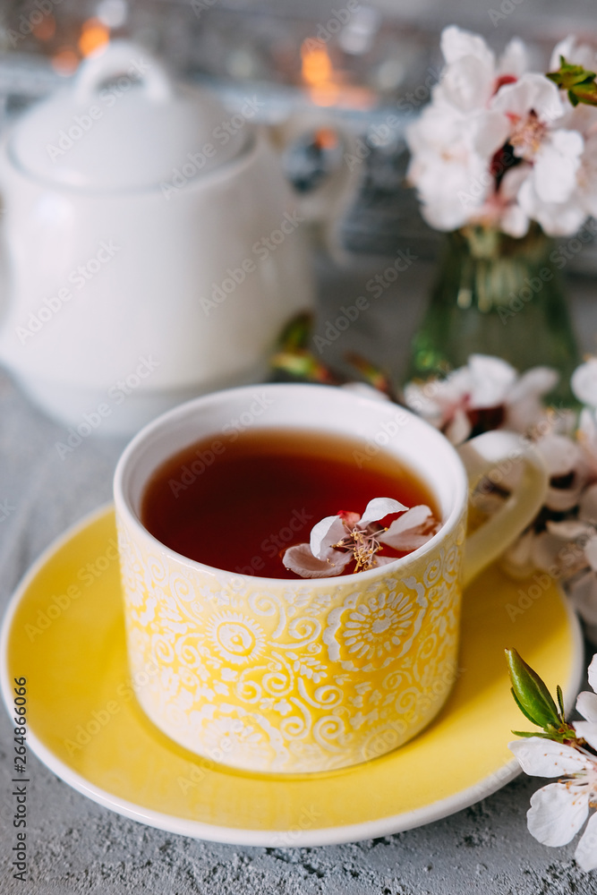 Tea served in a yellow teacup and saucer decorated with spring flowers Tea served in a yellow teacup and saucer decorated with spring flowers