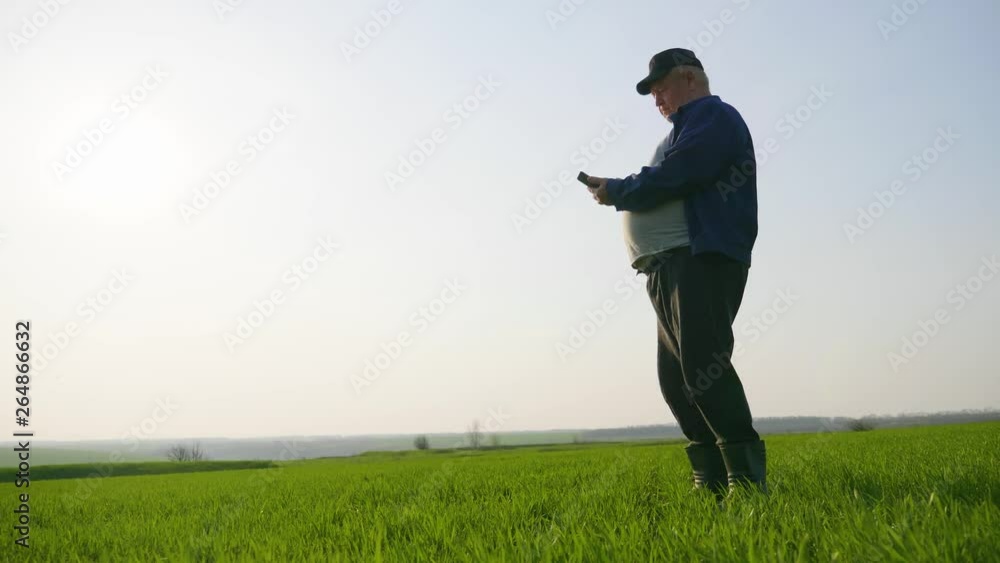 Mature farmer examining soil and using smartphone checking report of agriculture in a field. Mature farmer examining soil and using smartphone checking report of agriculture in a field.