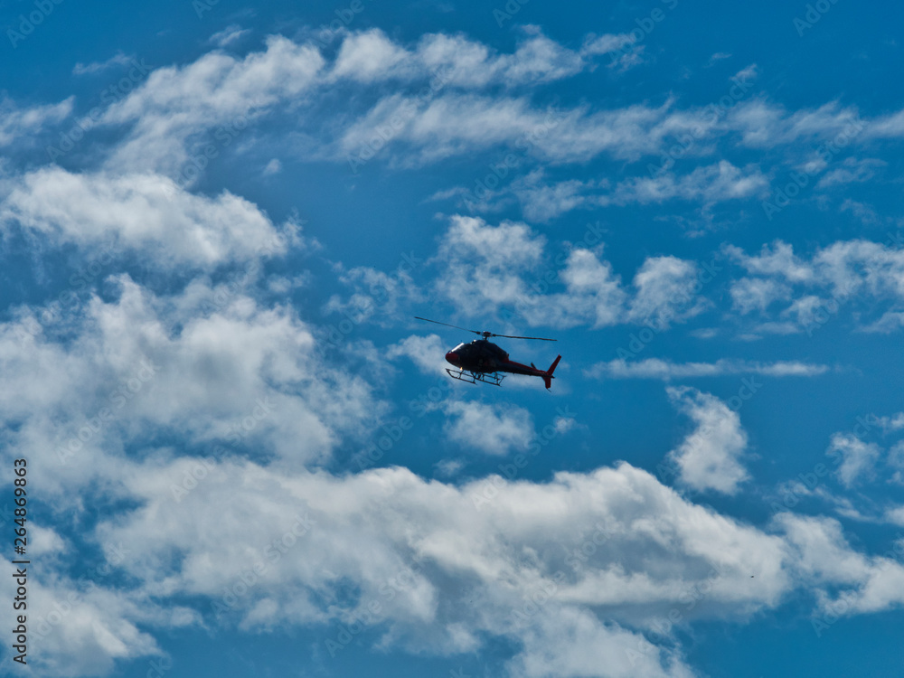 Flying helicopter airplane in blue sky with clouds