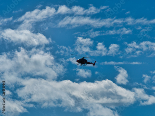Flying helicopter airplane in blue sky with clouds