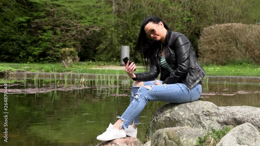 Brunette near the lake with a phone Brunette near the lake with a phone