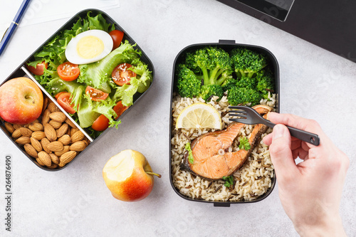 Man eating lunch from takeaway lunch box at working table. photo