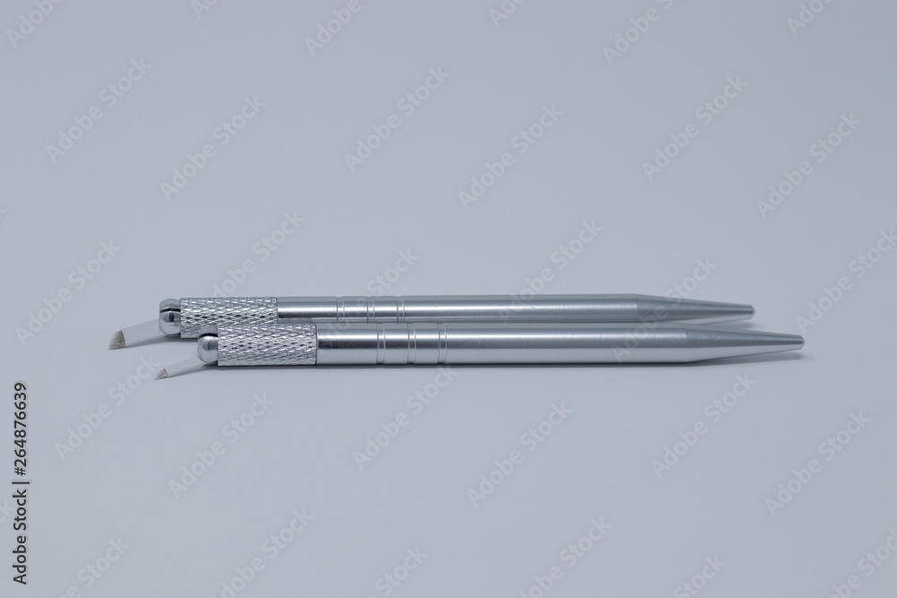 Two microblading pens with blades and needles used for applying permanent eyebrow makeup Two microblading pens with blades and needles used for applying permanent eyebrow makeup