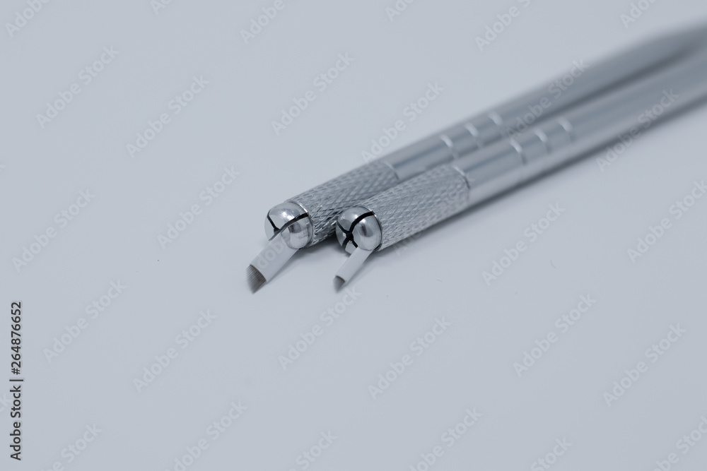 Two microblading pens with blades and needles used for applying permanent eyebrow makeup Two microblading pens with blades and needles used for applying permanent eyebrow makeup