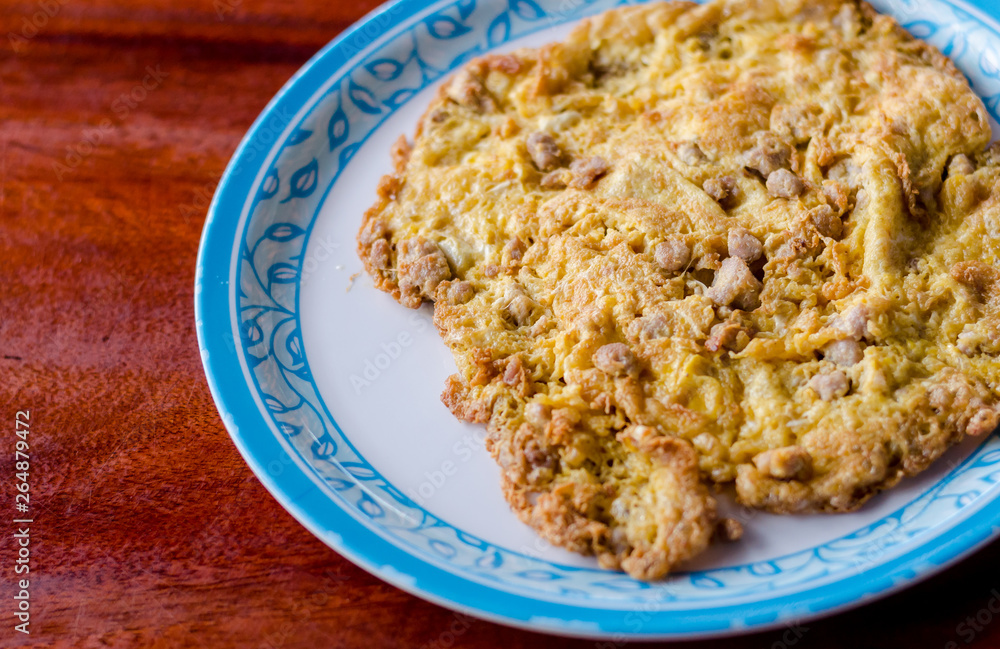 Thai fried omelet with pork on wooden table. soft focus Thai fried omelet with pork on wooden table. soft focus
