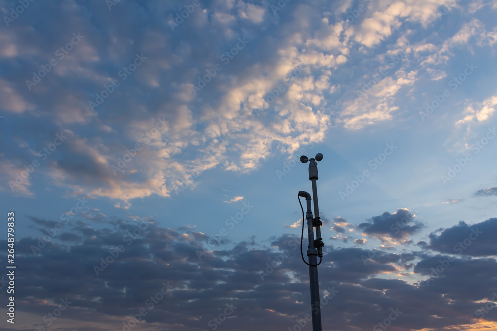Wind speed sensor or anemometer with blue sky and orange light in evening