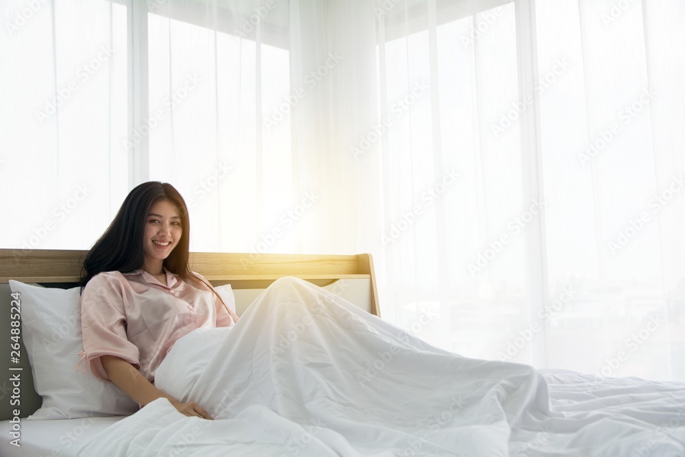 Portait of smiling lady wake up stretching herself welcome morning light on the bed Portait of smiling lady wake up stretching herself welcome morning light on the bed