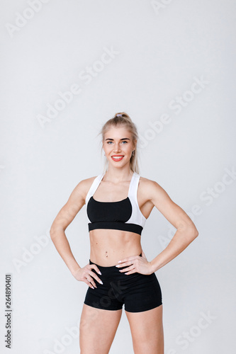 Portrait of beautiful young healthy woman in sportswear on gray.