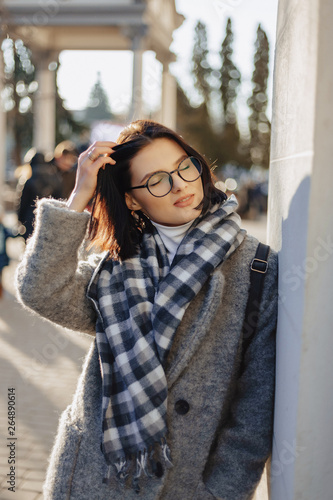 Attractive young girl wearing glasses in a coat walking on a sunny day © pressahotkey