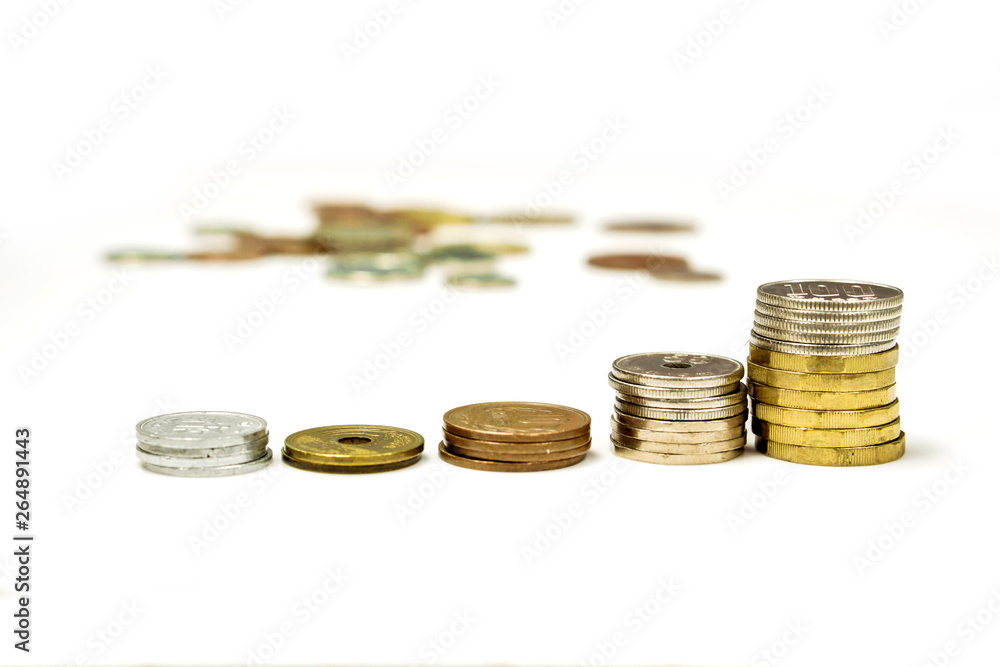 Side view and line up stacked of Japan Yen currency coins isolate on white and blurry coins spread background. Side view and line up stacked of Japan Yen currency coins isolate on white and blurry coins spread background.