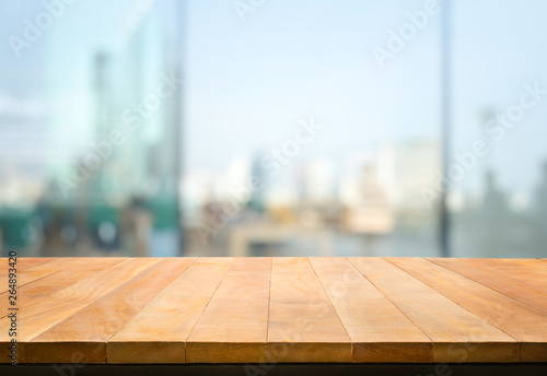 Wood table top on blur window glass,wall background with city view.For montage product display or design key visual