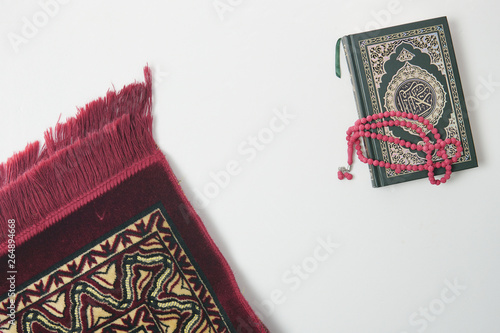 Holy Quran and rosary or tasbih with praying mat rug or sejadah