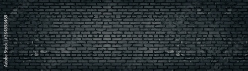 Wide old dark gray shabby brick wall texture. Black masonry panorama. Brickwork panoramic grunge background