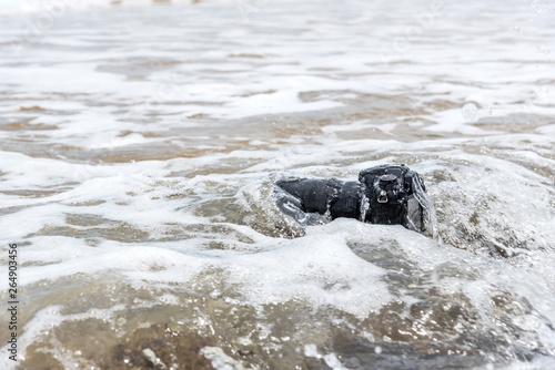 DSLR camera on stone beach wet from water sea wave