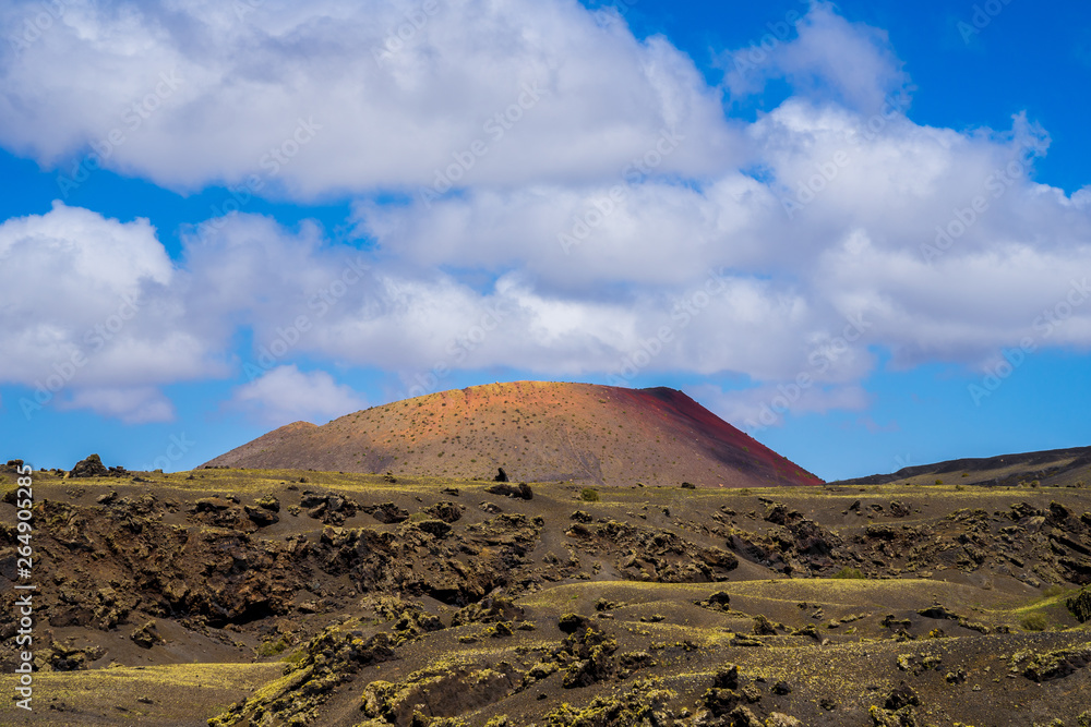 Spain, Lanzarote, Colorful red volcanic mount surrounded by rough solidified lava fields