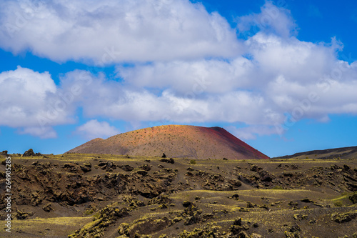 Spain, Lanzarote, Colorful red volcanic mount surrounded by rough solidified lava fields