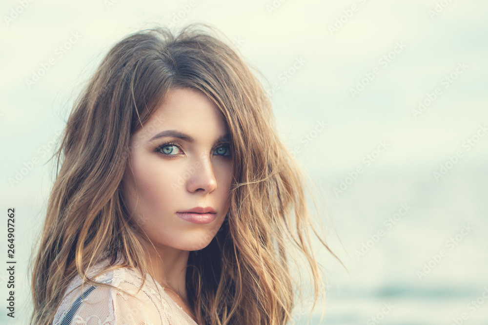 Young woman face closeup. Perfect model girl with long curly hairstyle. Natural beauty