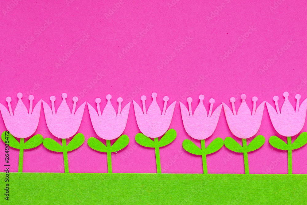 Abstract floral background of felt Easter tulip flowers of pink, purple and yellow on a plain background