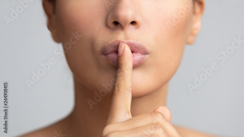 Women's secret. Woman holding finger on lips